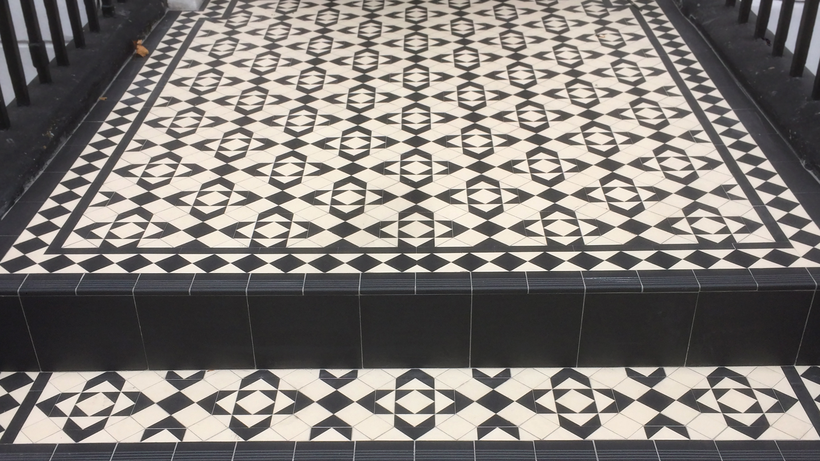 Black and white geometric mosaic tiles on entrance step and landing.