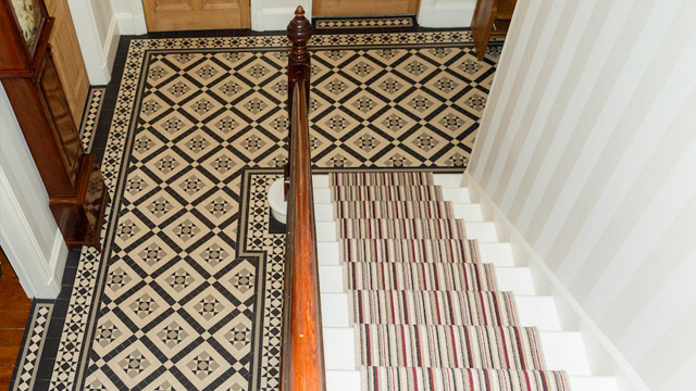 Complex hallway space tiled in Victorian mosaics, featuring multiple door thresholds.