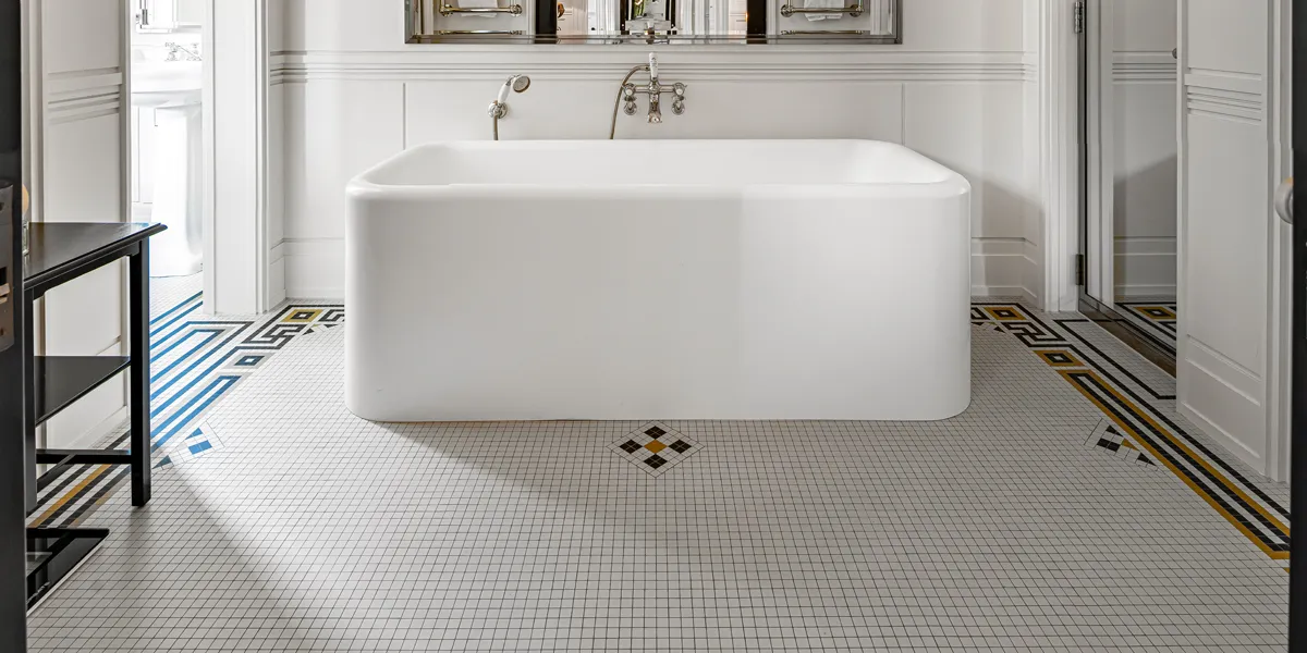 Art Deco style ceramic micro mosaic floor tiles, featuring black and yellow border detailing on the floor of a bespoke hotel bathroom.